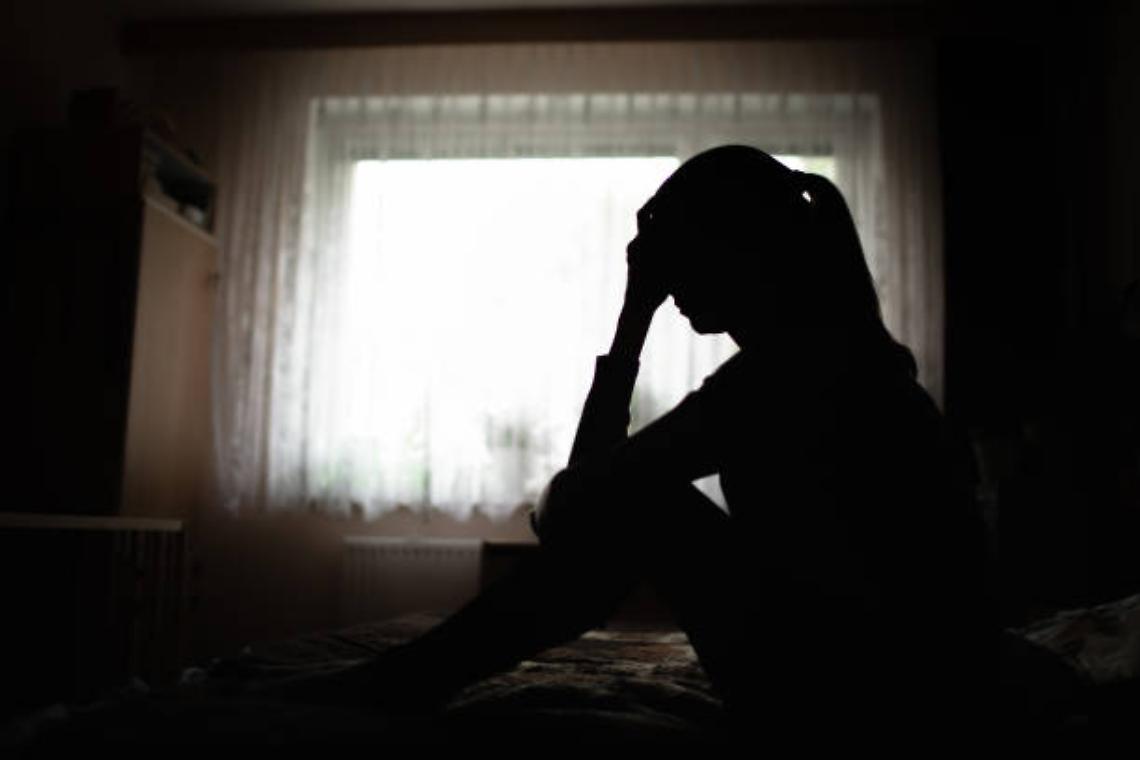 Woman sitting on bed feeling sleepless.