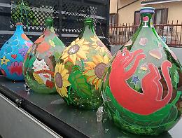 Vecchie damigiane dipinte dai bimbi del paese, diventano decorazioni di Natale