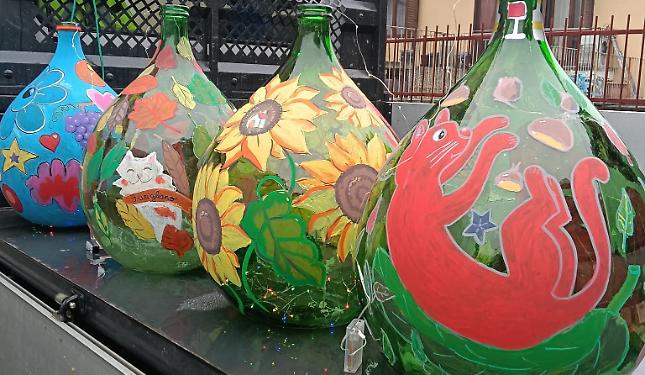 Vecchie damigiane diventano decorazioni natalizie, dipinte dai bimbi del paese